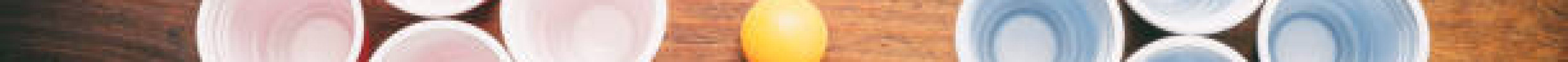 Beer pong, college party game. Plastic red and blue color cups and ping pong balls on wooden background, top view